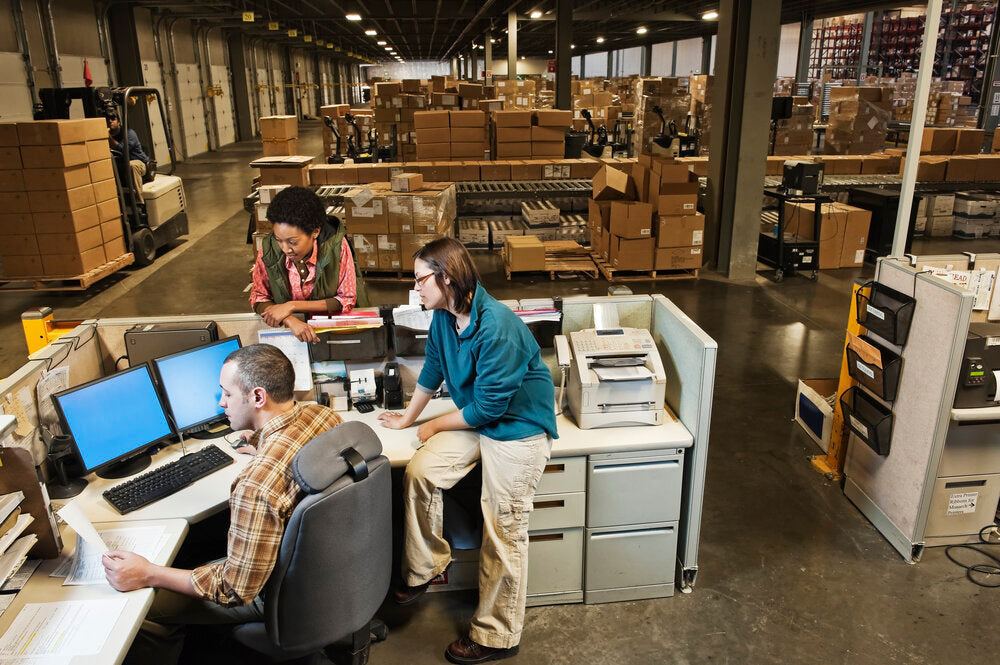 Office workers reviewing documents on a computer, planning virtual office setup and warehouse logistics for efficient remote business operations.