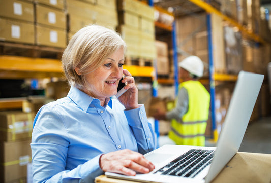 Senior businesswoman using laptop inside a warehouse